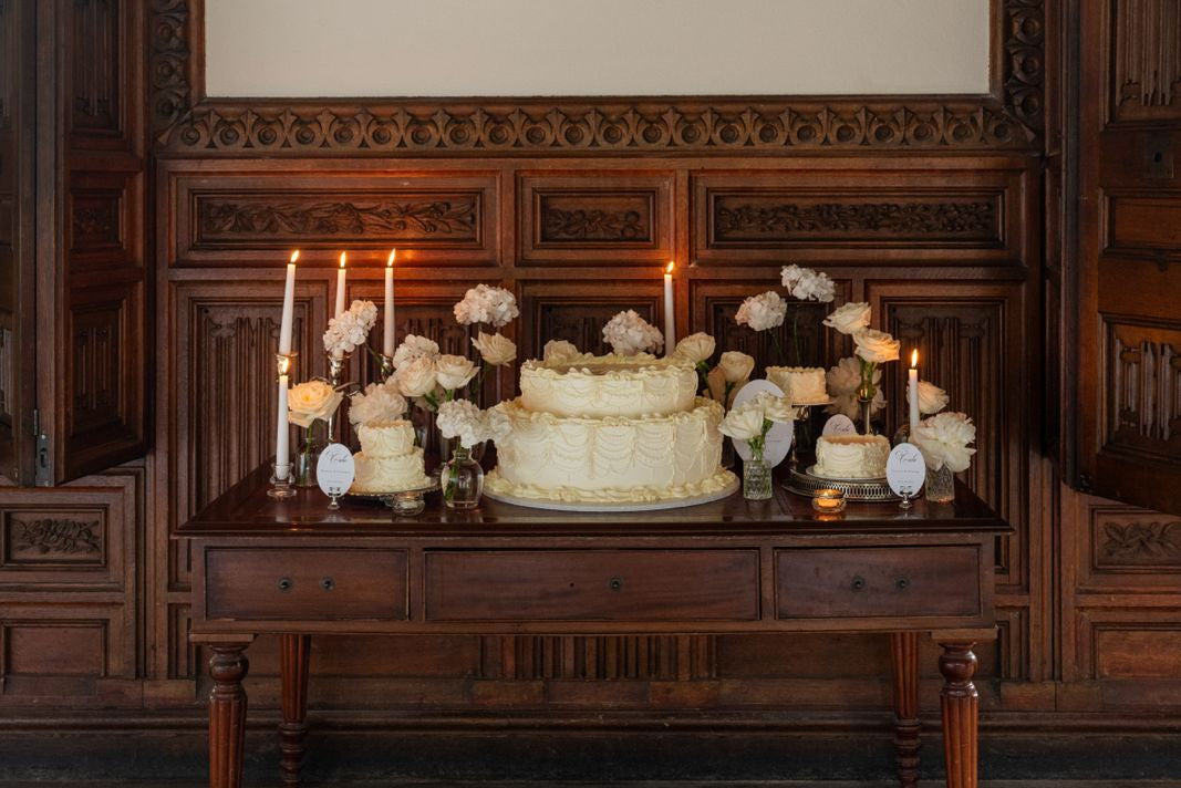 Decorative setup with a cake and flowers on a wooden table below a portrait in Ashton Court Mansion